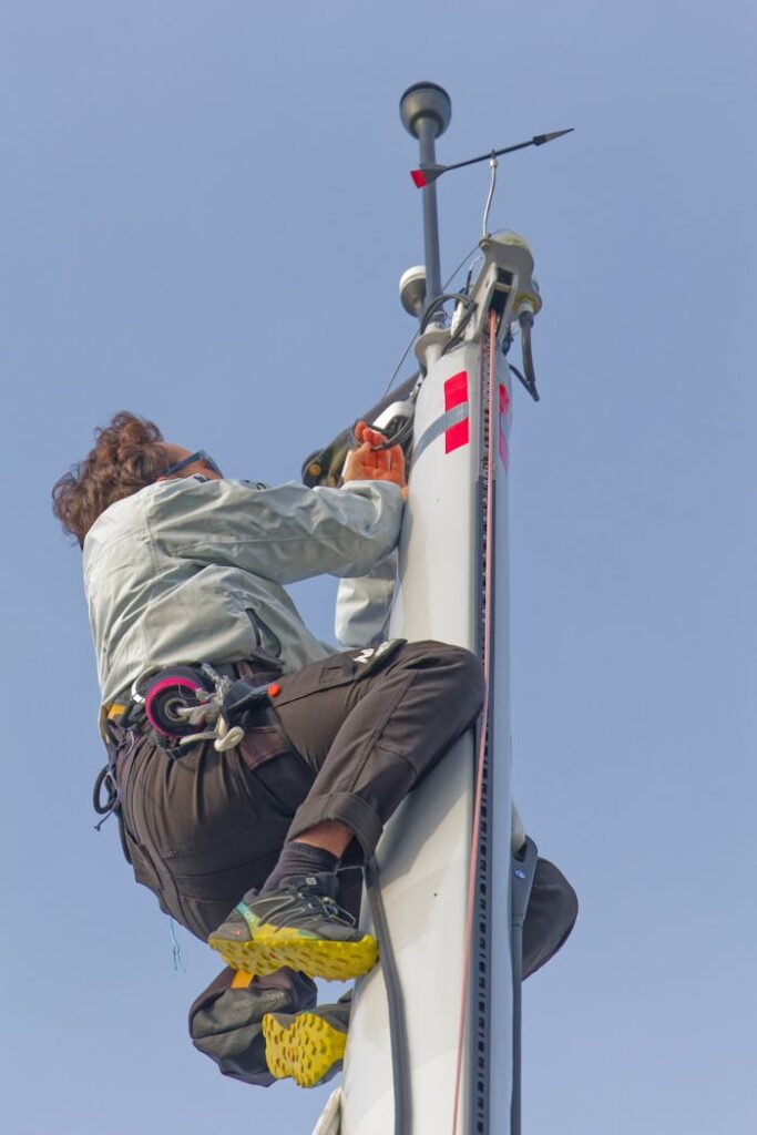 A skilled technician climbing a mast in Les Sables-d'Olonne, showcasing expertise in sailing technology.